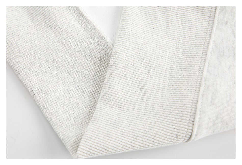 Close-up of light heather-gray ribbed sweatshirt fabric and stitched seam.