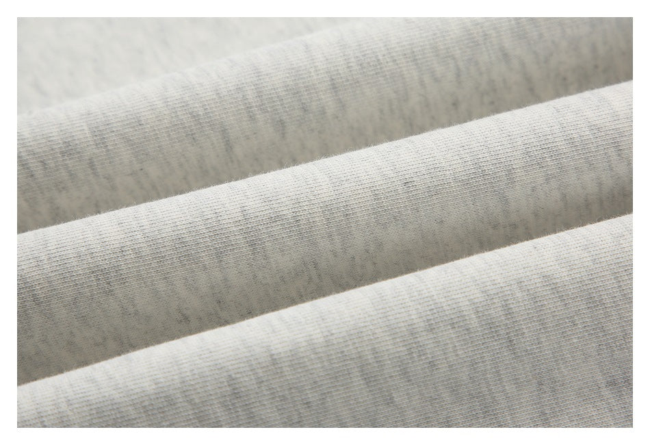 Close-up of light heather-gray fabric arranged in overlapping folds, showing its knit texture.