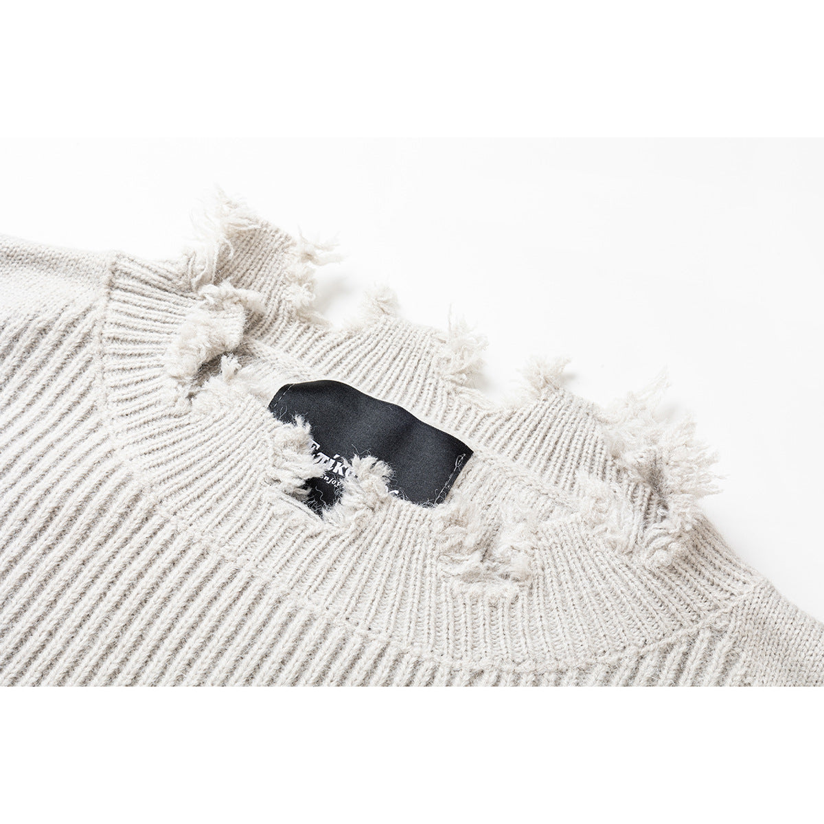 Close-up of an ivory rib-knit sweater neckline with distressed fraying and a black neck label.
