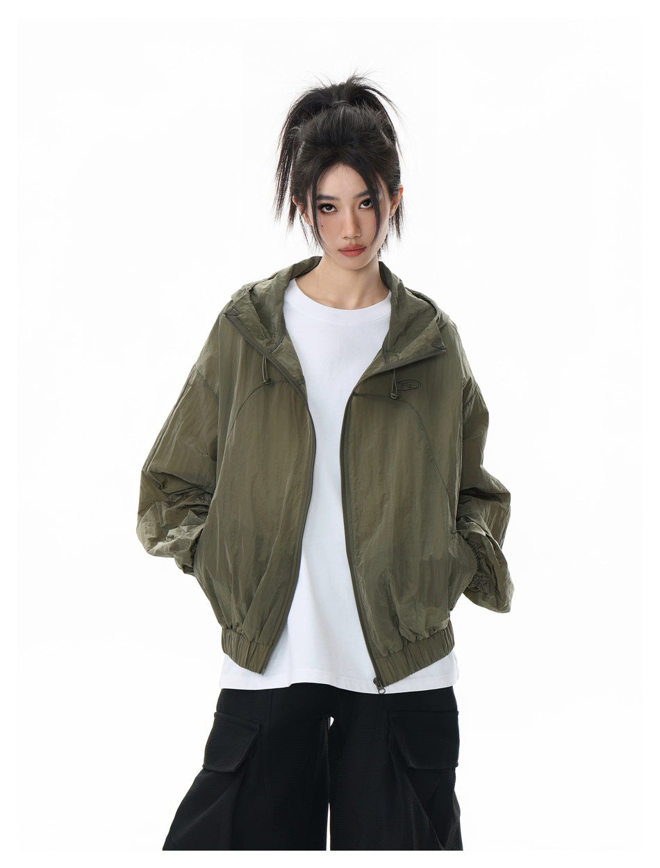 Front view of a model wearing an open olive hooded jacket over a white shirt and black cargo pants.