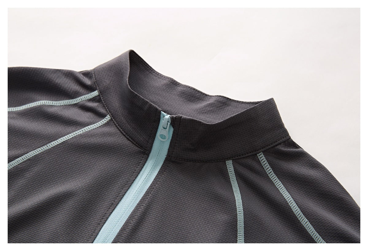 Close-up of a charcoal top's stand collar and pale blue front zipper with contrast stitching.