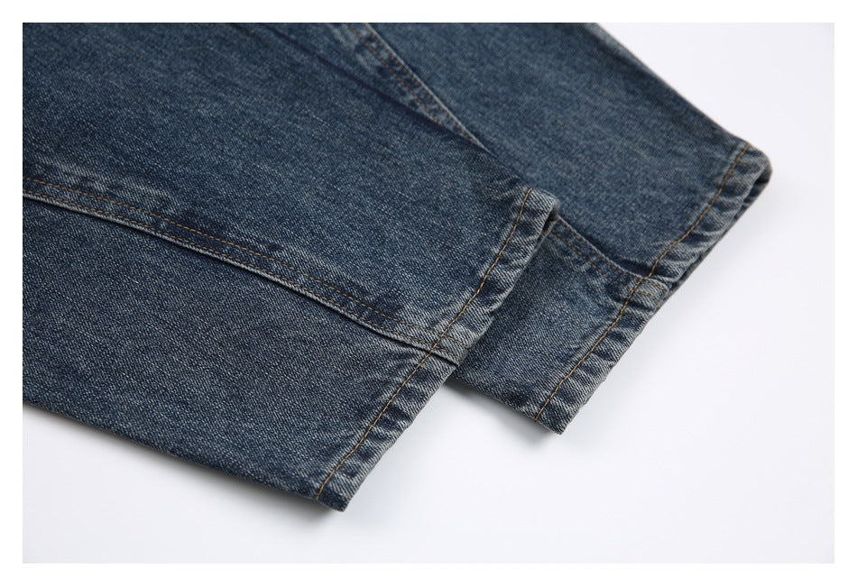 Close-up of dark blue denim jeans showing two finished hems and contrast stitching.