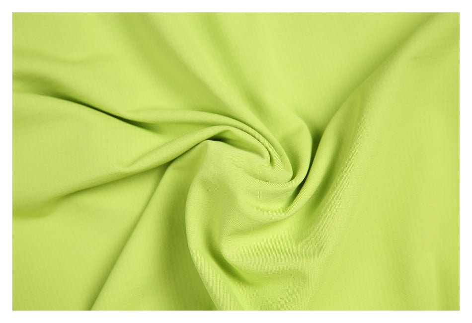 Close-up of smooth lime-green garment fabric gathered into soft folds.