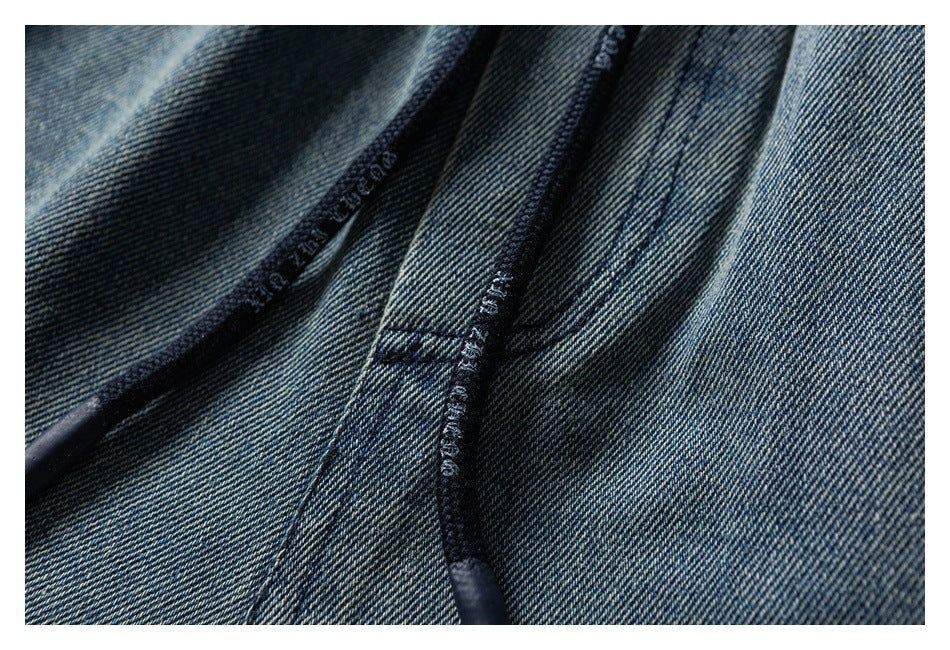 Close-up of dark blue denim with a curved seam and dark overlock stitching.