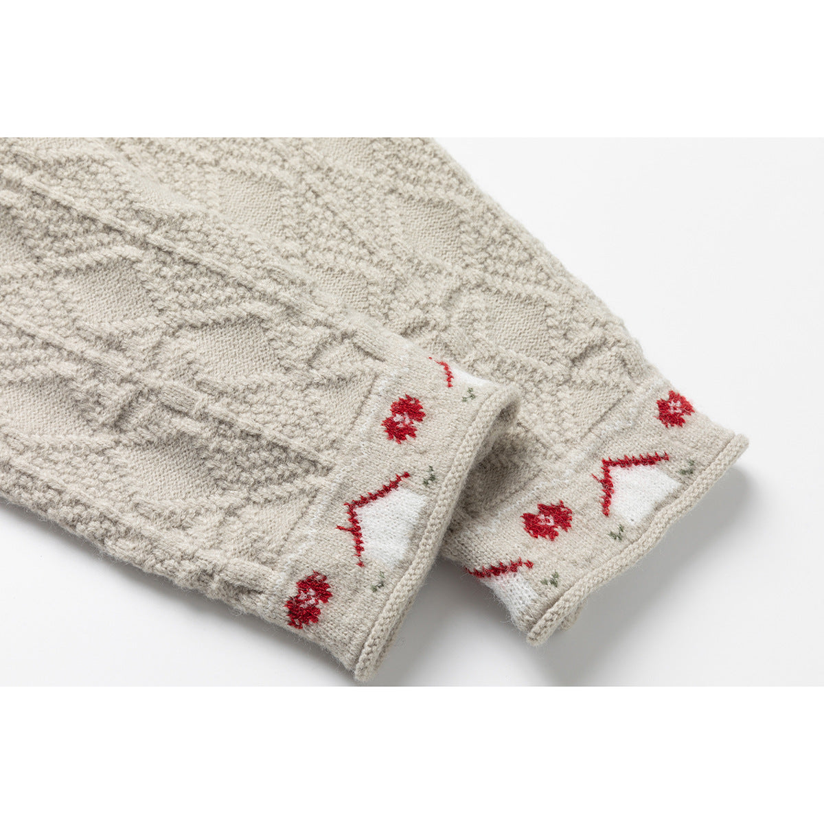 Close-up of cream knitted cardigan cuffs with red floral and geometric pattern accents.