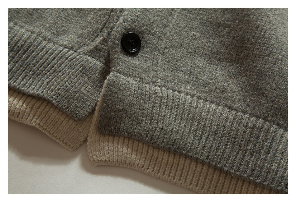 Close-up of a black button and ribbed taupe-gray knit trim layered over beige ribbing.