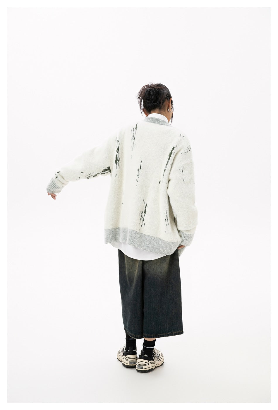 Rear view of a person wearing an ivory fuzzy knit cardigan with dark abstract streaks and gray ribbed trim.