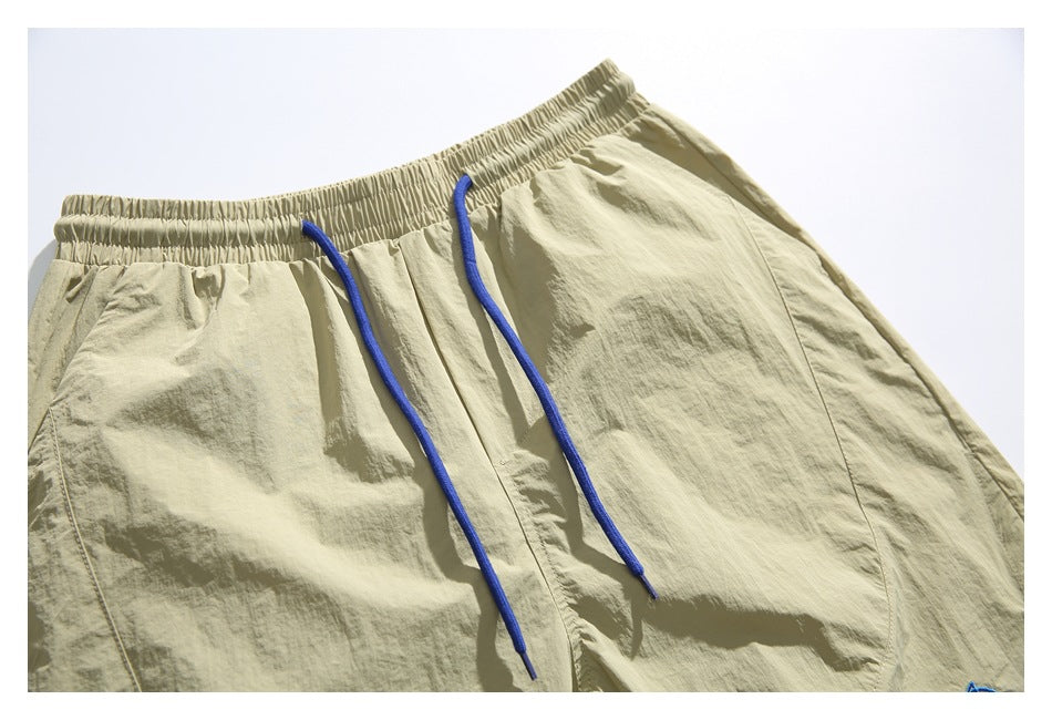 Close-up of the shorts' elastic waistband and long royal-blue drawstrings against pale khaki fabric.