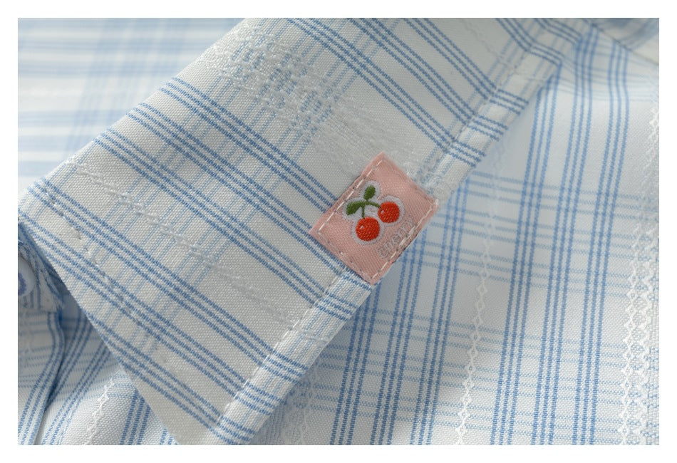 White and blue plaid shirt fabric with a small pink patch embroidered with cherries.