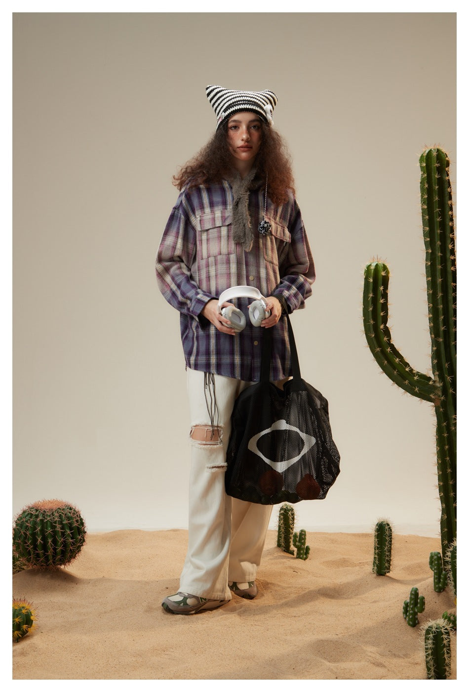 Model wearing a purple plaid shirt jacket with chest pockets, paired with white trousers and a striped beanie.