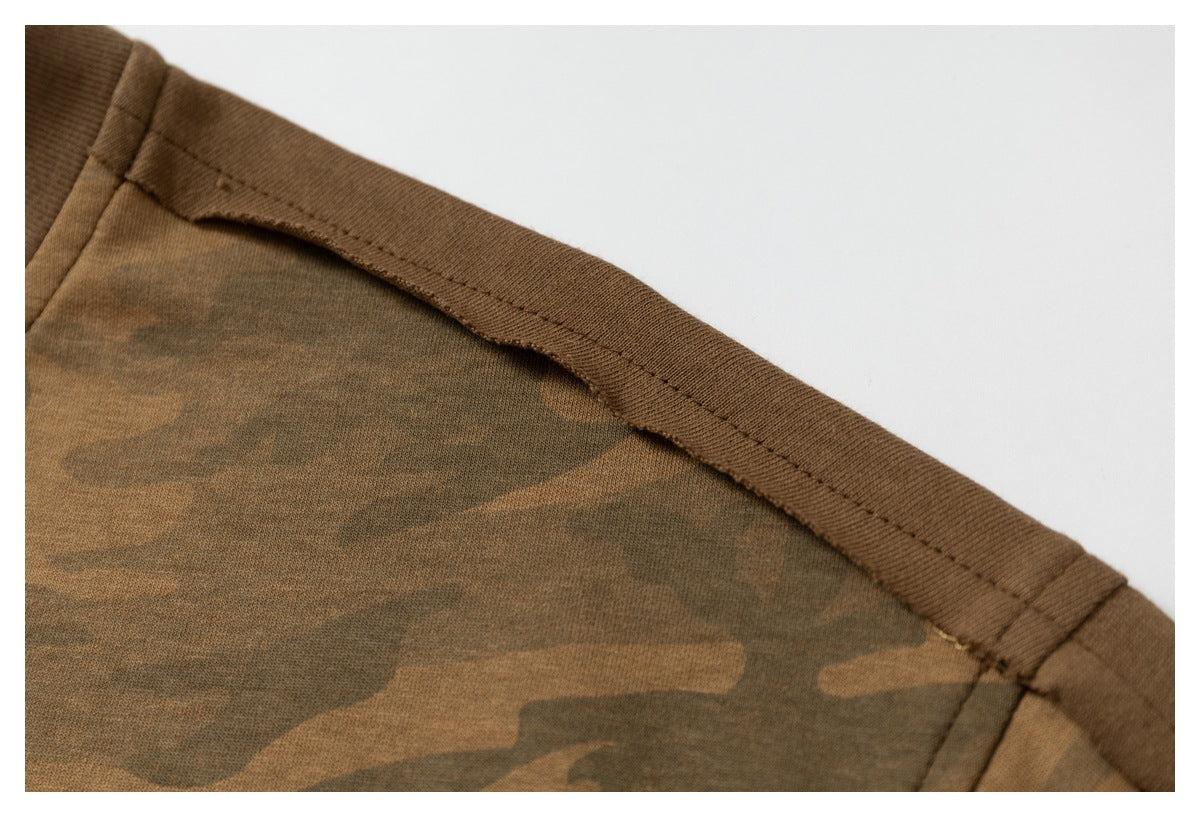 Close-up of a brown camouflage garment seam with brown binding and visible stitching.