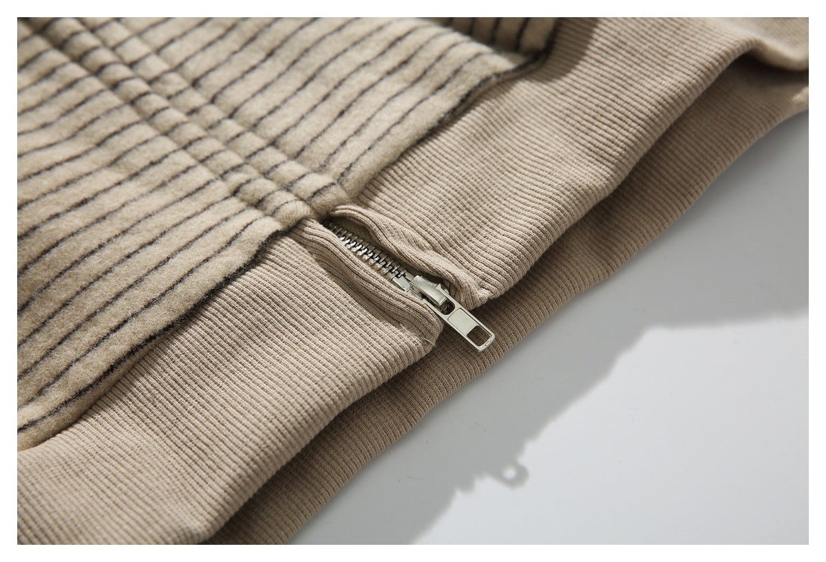 Close-up of the beige striped jacket's metal zipper where it meets the ribbed hem.