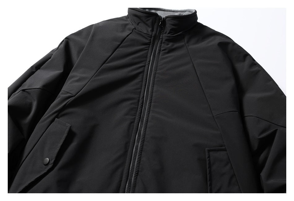 Black zip-front jacket laid flat, with a gray-lined stand collar, angled seams, and flap pockets.