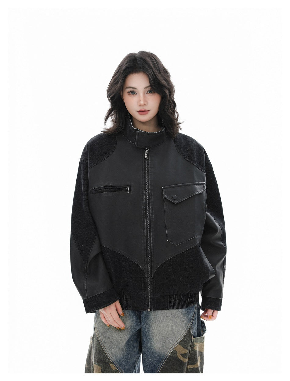 Model wearing a black zip-front stand-collar jacket with patchwork panels and chest flap pocket, front view