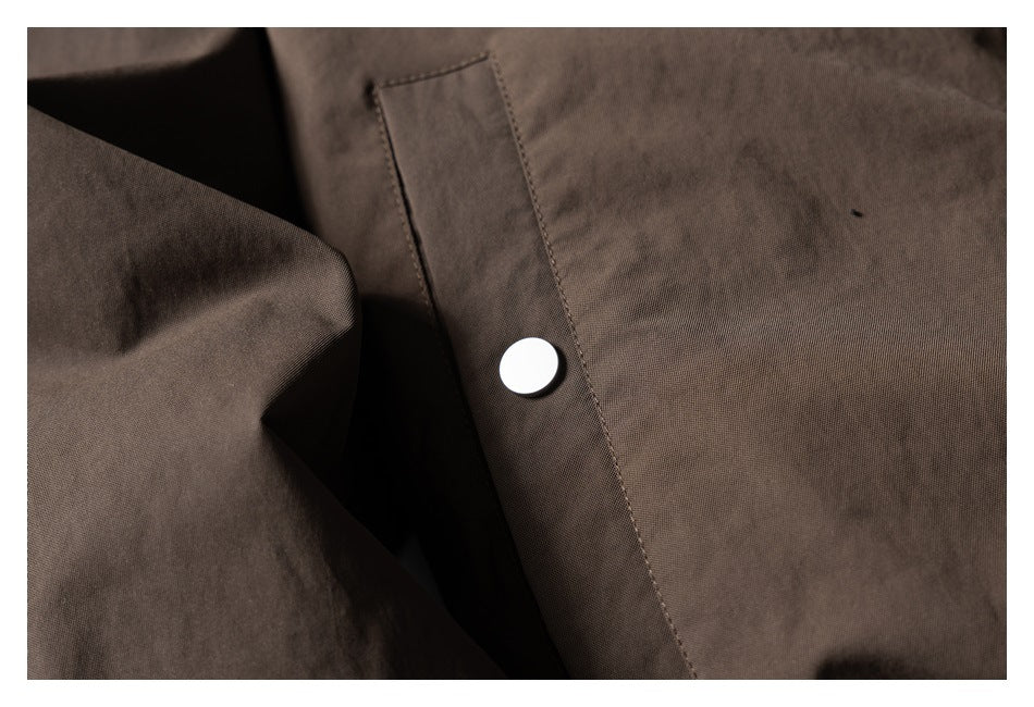 Close-up of a dark brown jacket panel and placket with a silver snap fastener.