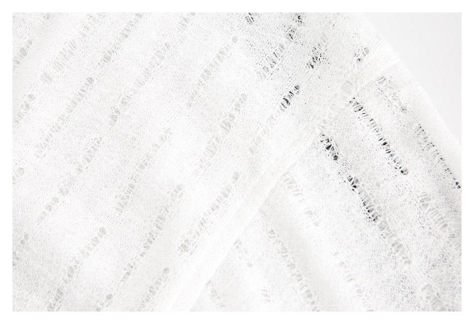 Close-up of white open-knit fabric showing its irregular ladder-like texture and folds.