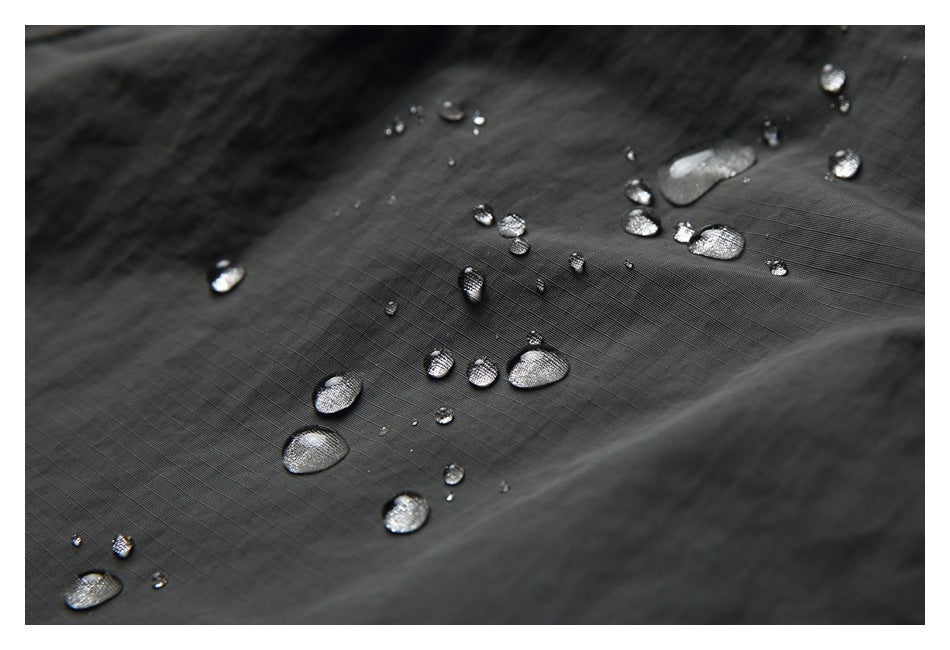 Close-up of dark charcoal fabric with water droplets beading on its surface.