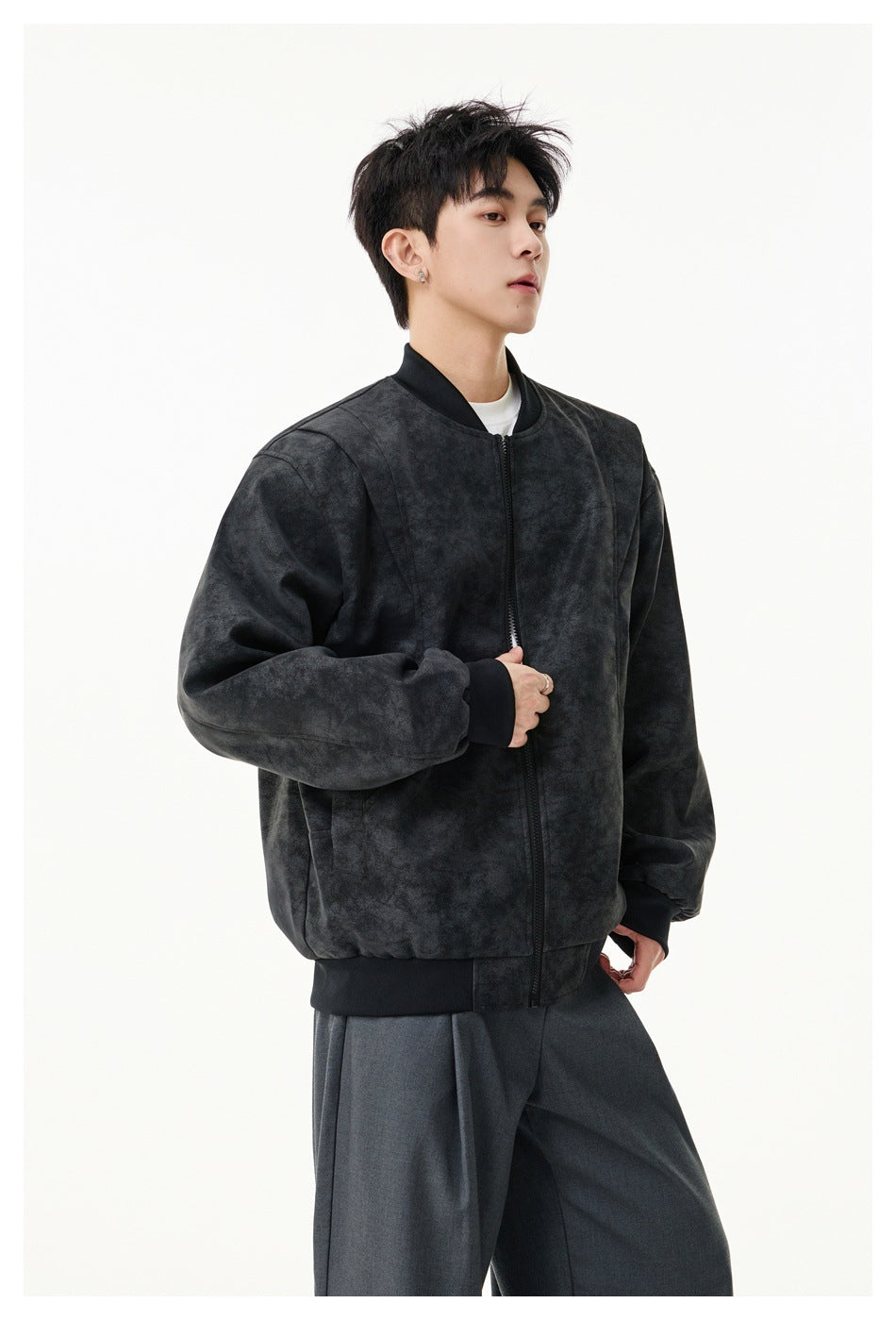 Three-quarter view of a model in a dark charcoal mottled zip-front jacket with ribbed trims.
