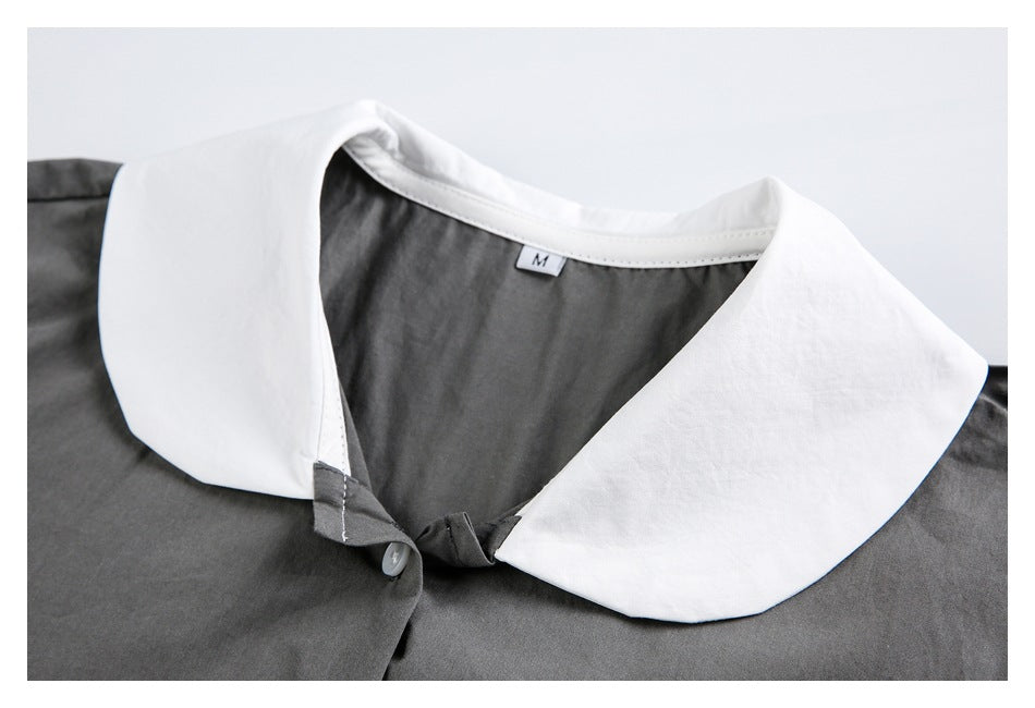 Cropped front view of a charcoal gray shirt with a wide white collar and white buttons.