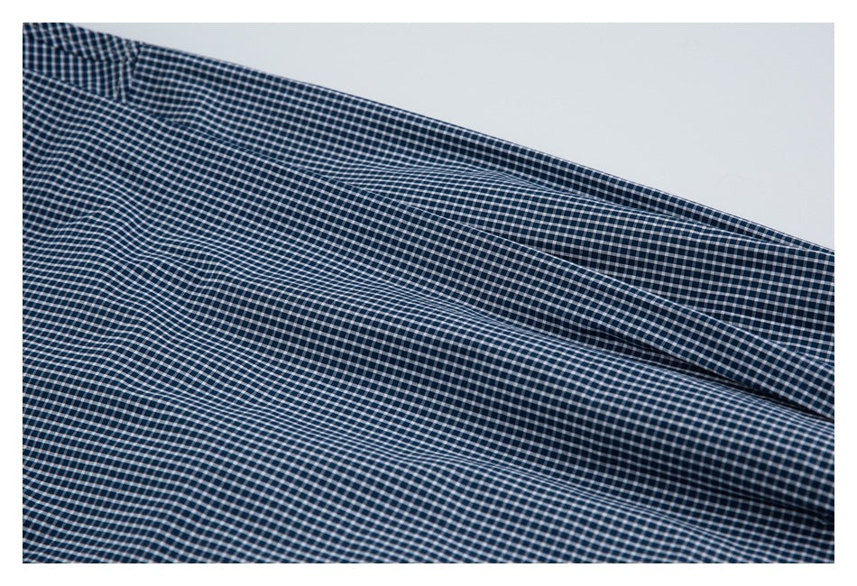 Close-up of navy-and-white checked shirt fabric arranged in soft folds.