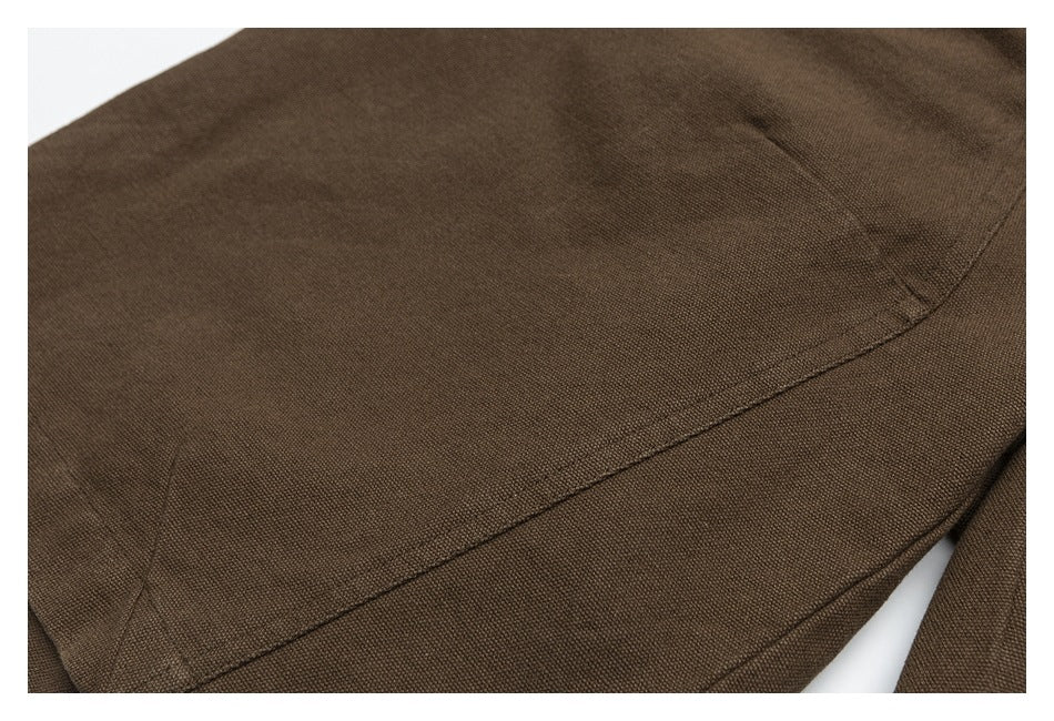 Close-up of a curved stitched seam and panel on the brown trousers.