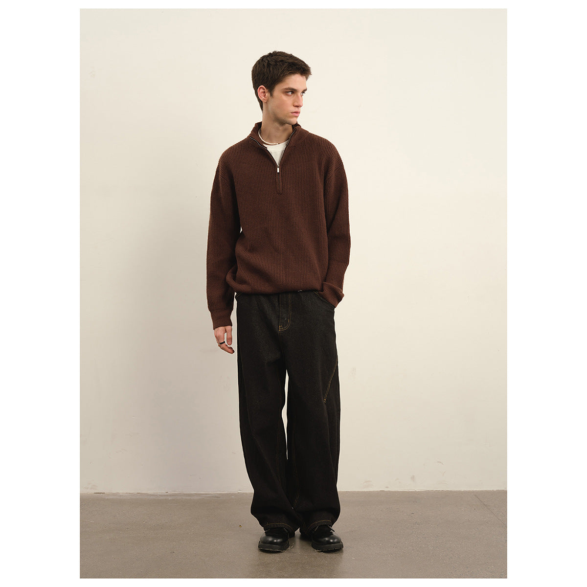 Model wearing a dark brown quarter-zip sweater and wide-leg black trousers.