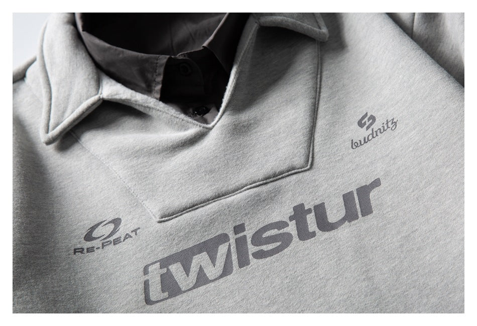 Close-up of a light gray collared sweatshirt with dark buttons and several printed chest logos.