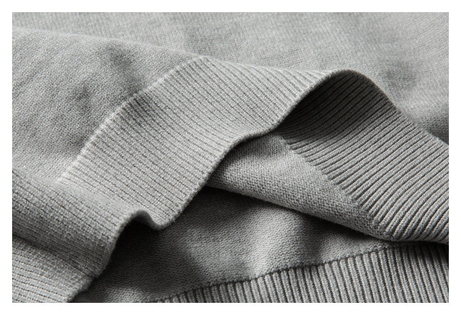 Close-up of folded ribbed edges and knit texture on a light gray sweater.