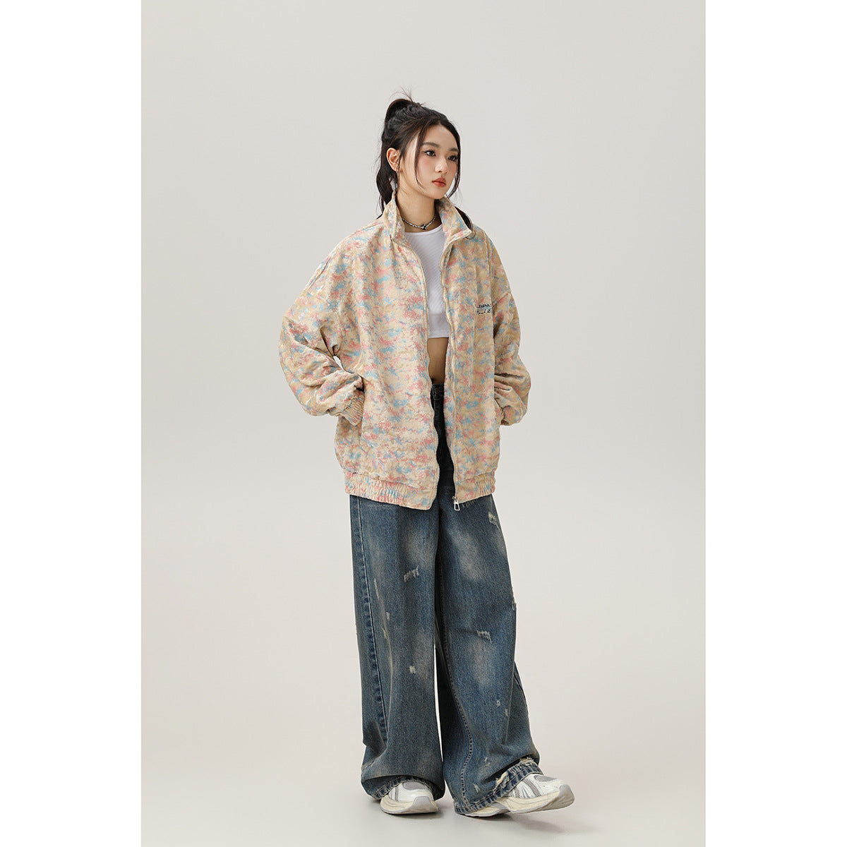 Model wearing an oversized pastel multicolor zip-up jacket with a high collar and elastic cuffs.
