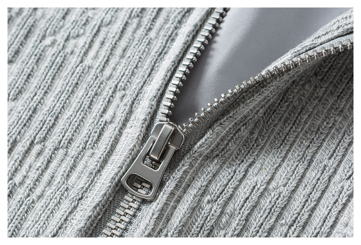 Close-up of the light gray rib-knit sweater's open metal front zipper.