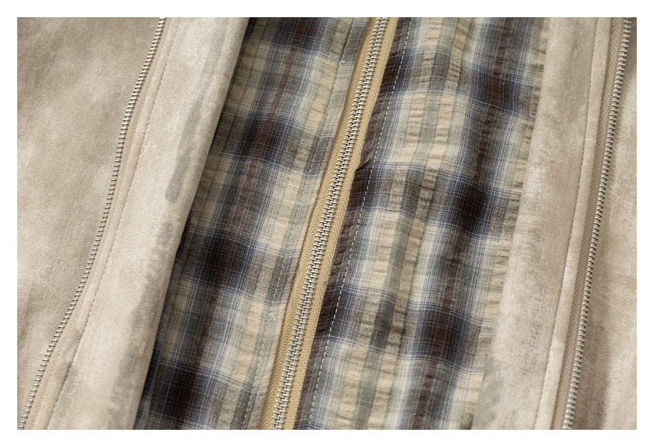 Close-up of a beige jacket with a metal zipper and a brown, gray, and cream plaid lining.