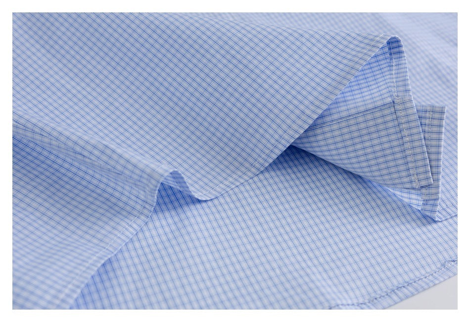 Close-up of light blue checked shirt fabric folded to show a stitched edge.