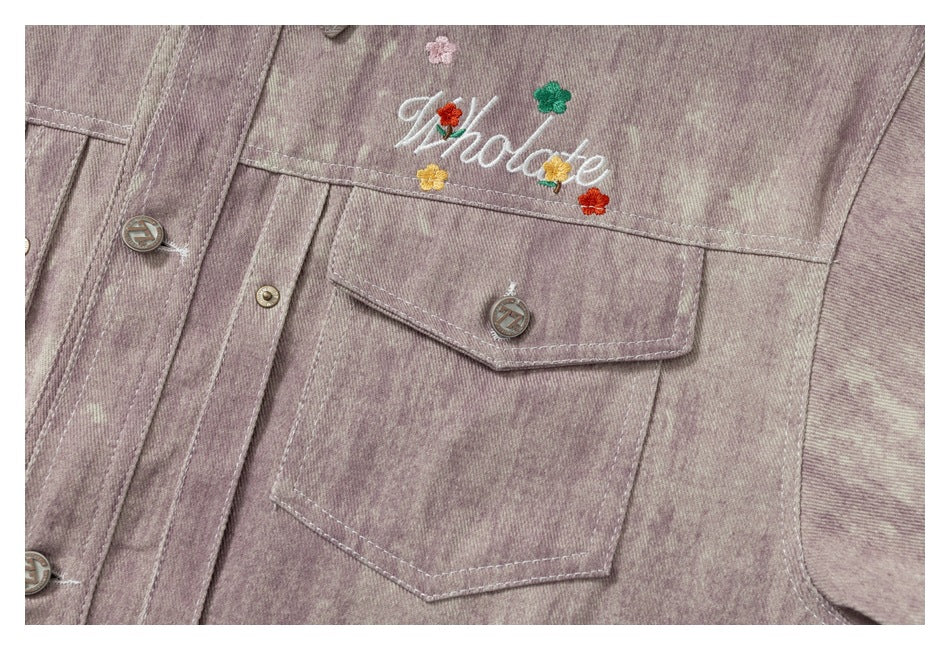 Close-up of the jacket's embroidered floral lettering, button-front placket, and flap chest pocket.