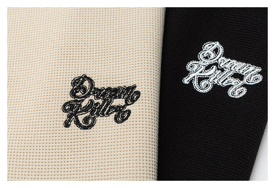 Close-up of embroidered script on beige and black textured knit fabric.