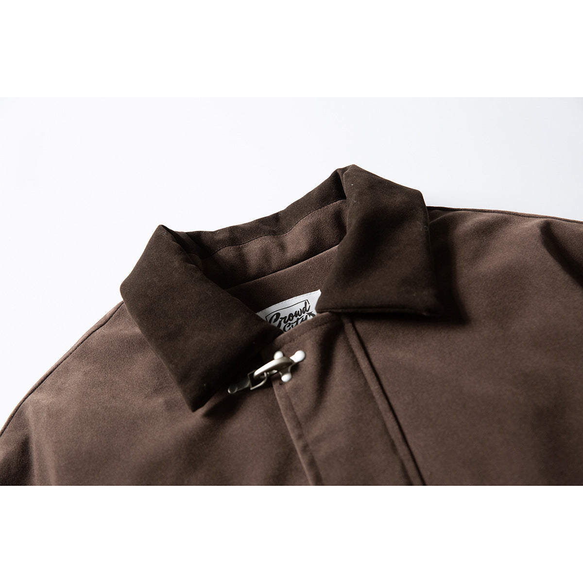 Close-up of a dark brown jacket collar with a silver clasp and a partially visible neck label.
