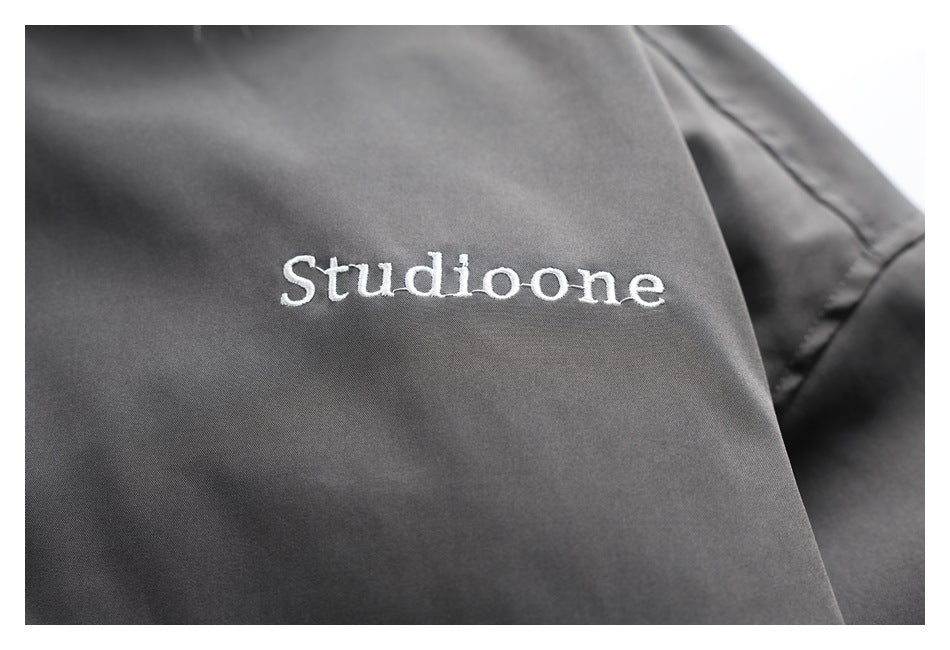 White Studioone embroidery on the charcoal jacket fabric.