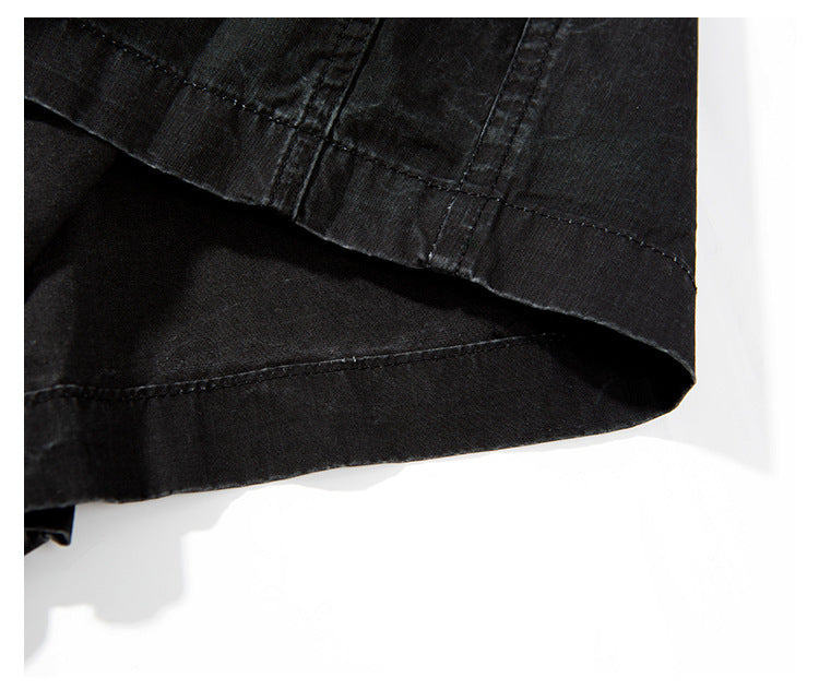 Close-up of the layered, stitched hem on black shorts.