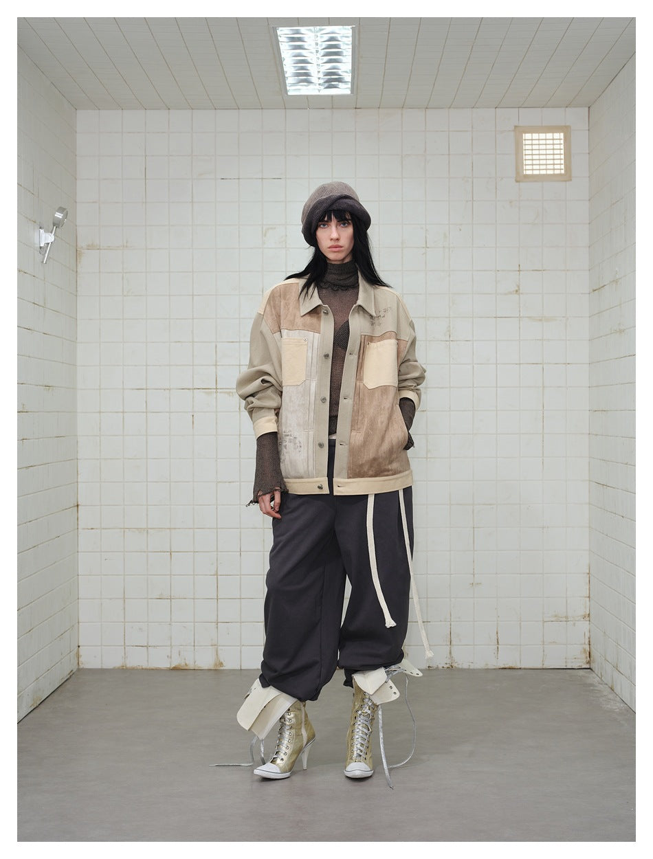 Front view of a model wearing the patchwork khaki and brown jacket with dark pants in a tiled room