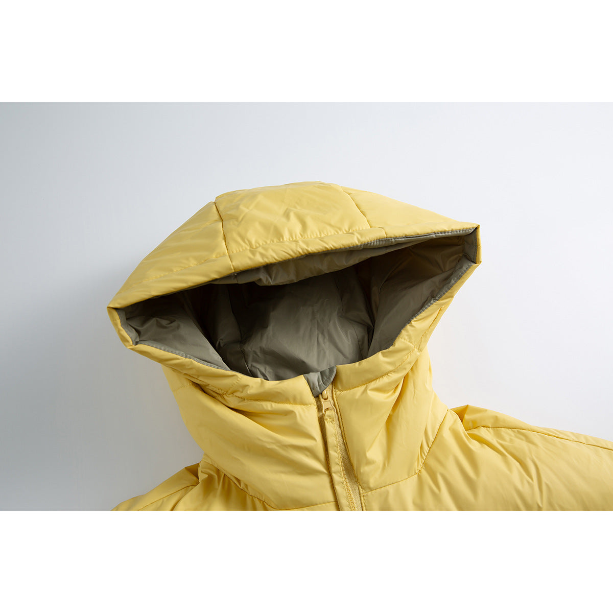 Close-up of a yellow puffer jacket with its hood open, showing the gray lining and front zipper.
