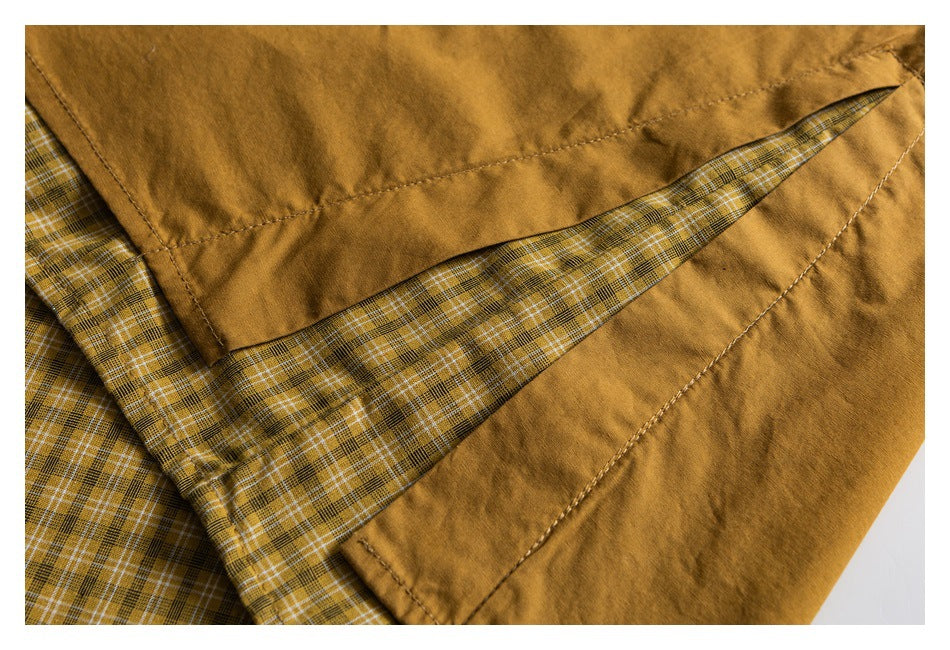 Close-up of a mustard-brown garment with stitched seams and yellow, black, and white plaid lining.