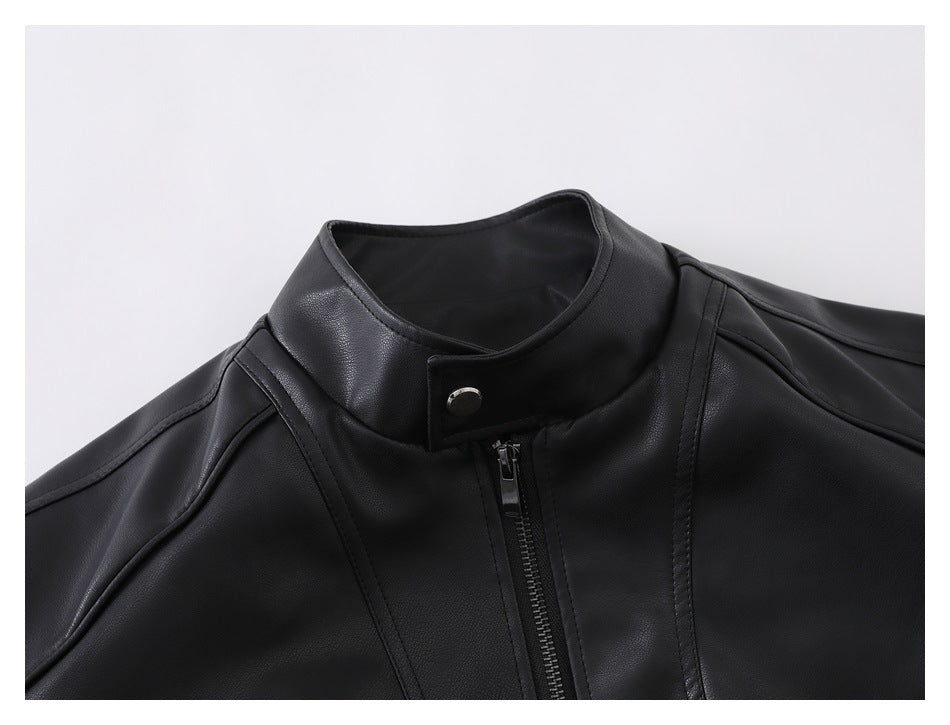 Close-up of a black jacket's stand collar, snap tab, front zipper, and stitched shoulder panels.