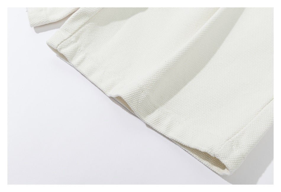 Close-up of the stitched hem on an ivory textured garment.