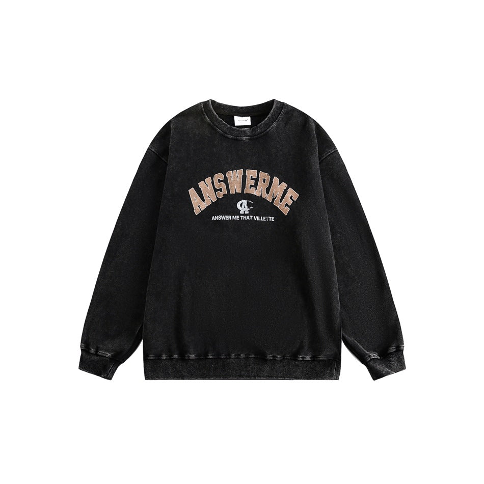 Black washed crewneck sweatshirt flat lay with arched tan ANSWERME graphic and ribbed collar, cuffs and hem