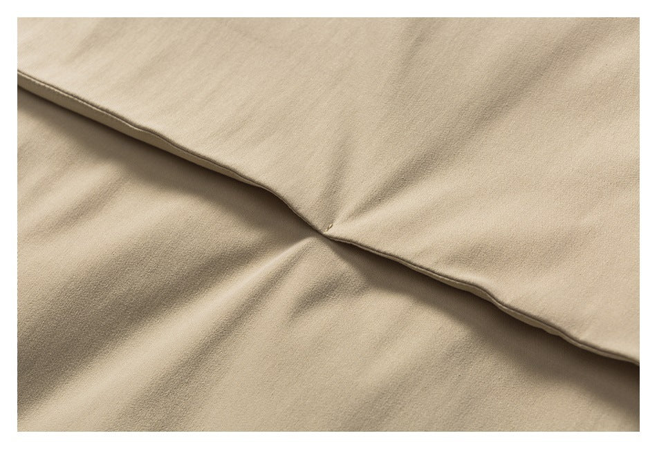 Close-up of beige fabric with a curved folded edge and visible stitching.