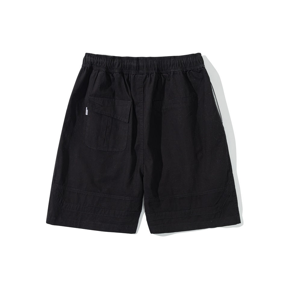 Back view of black shorts with elastic waistband, flap back pocket, welt-style pocket and stitched hem panels