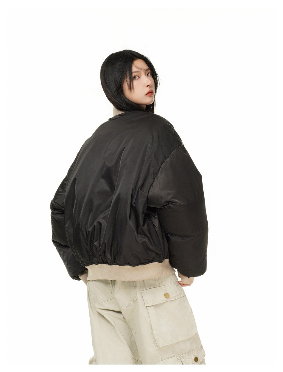 Model turned away, showing the back of an oversized black jacket with a beige ribbed hem and cuffs.