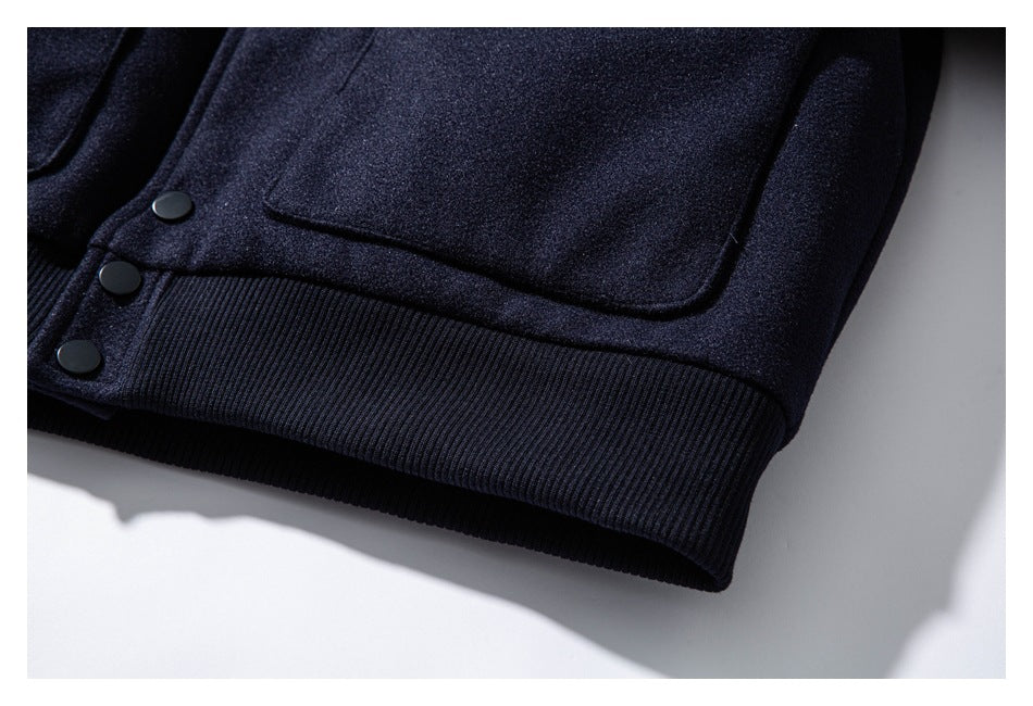 Close-up of a dark navy jacket pocket, snap buttons, and wide ribbed hem.