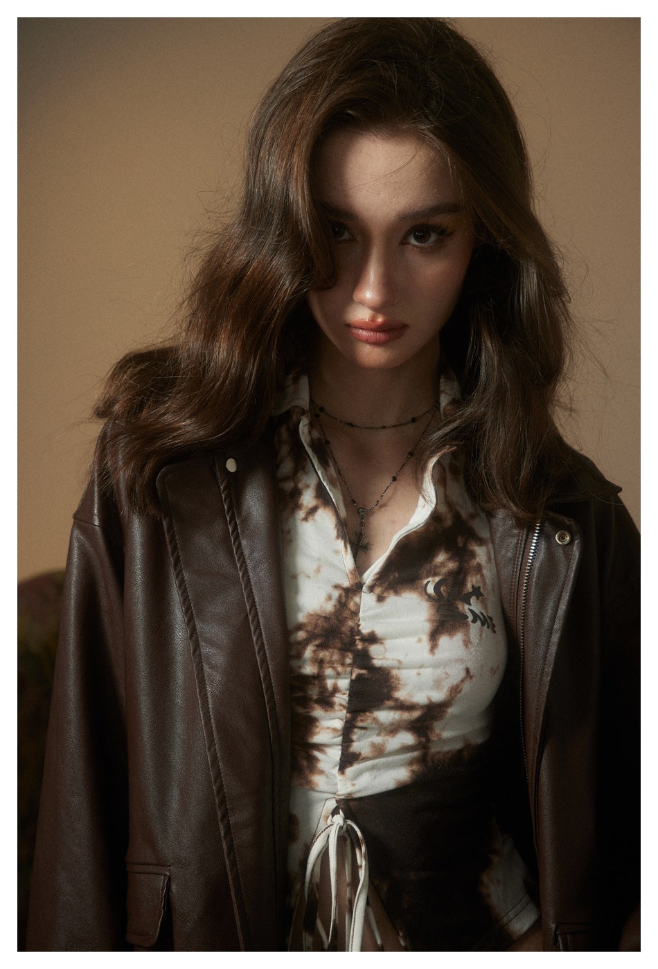 Close-up of a model wearing an oversized dark brown jacket over a cream-and-brown printed top.