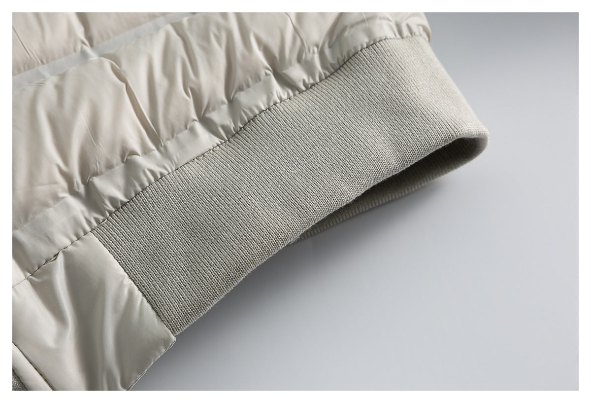 Close-up of a wide gray rib-knit cuff on the sleeve of a cream quilted puffer jacket.
