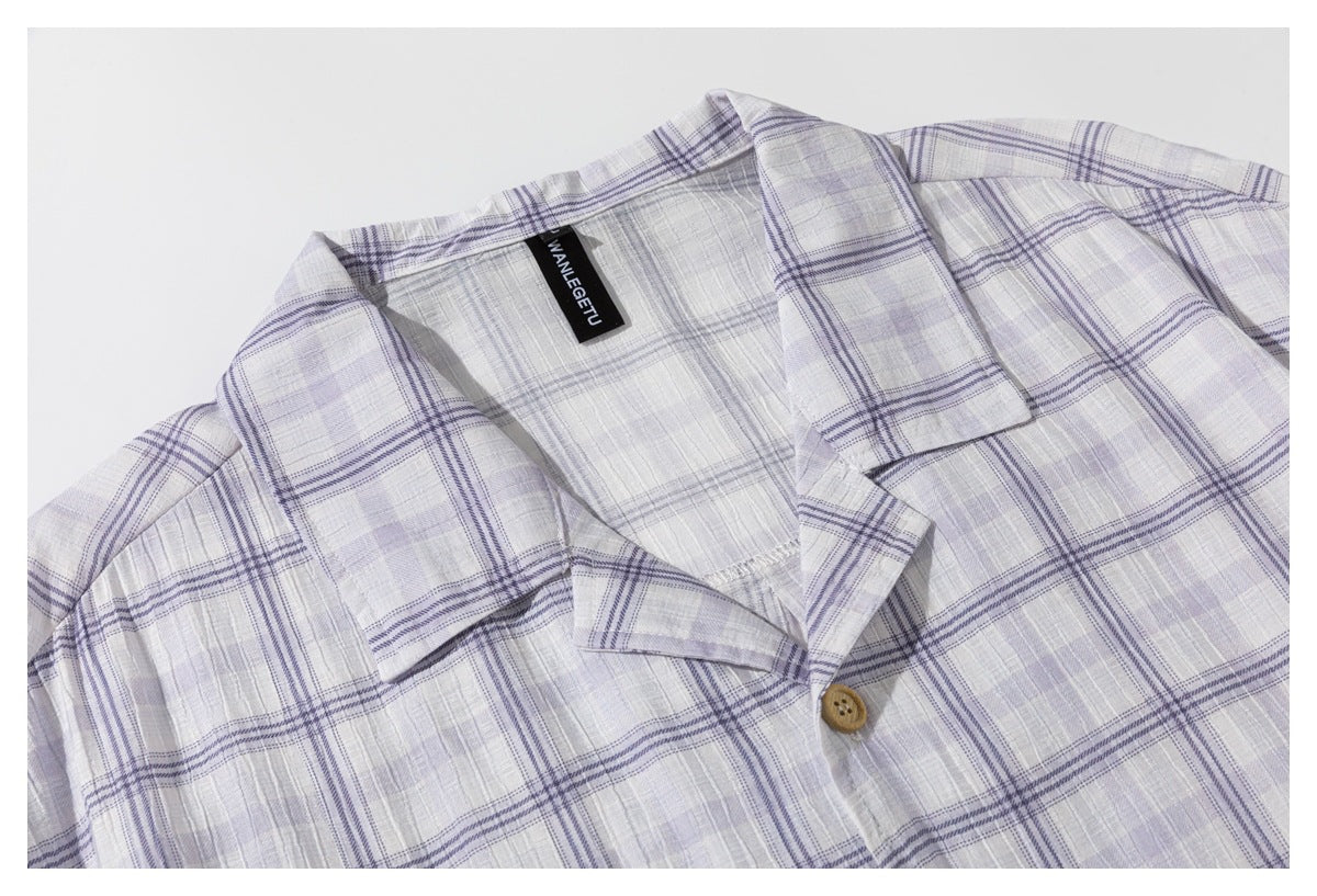 Close-up of the open collar, wooden button, and pale lavender plaid fabric of a shirt.